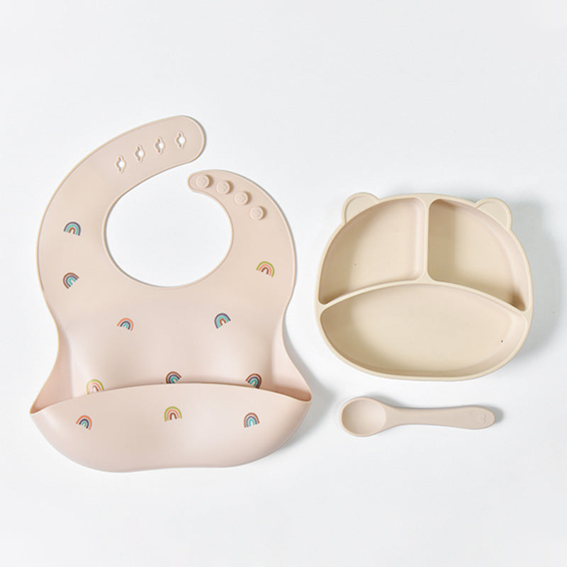 Beige baby bib, bowl, and spoon set with rainbow patterns on a white background